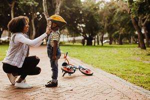 A woman buckling on a child's bicycle helmet